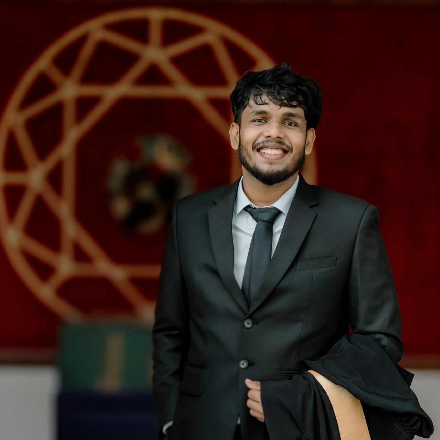 Portrait of Powsihan Indrakumar in a dark suit, smiling